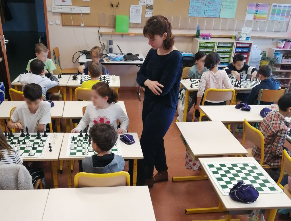 Animatrice surveillant les enfants sur leur échiquier. 
