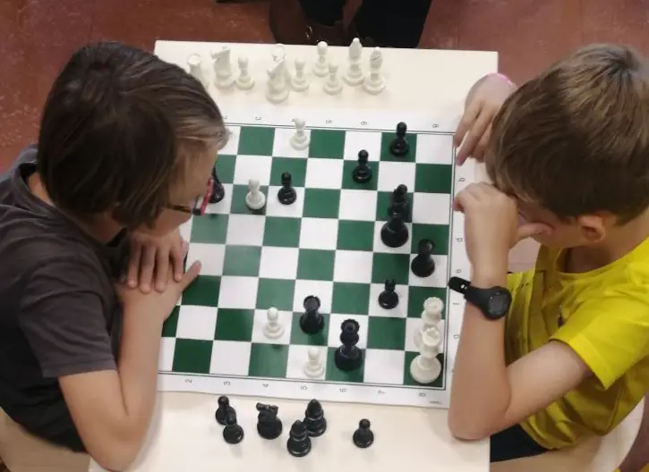 Deux enfants jouant aux échecs sur un échiquier dans une salle de classe